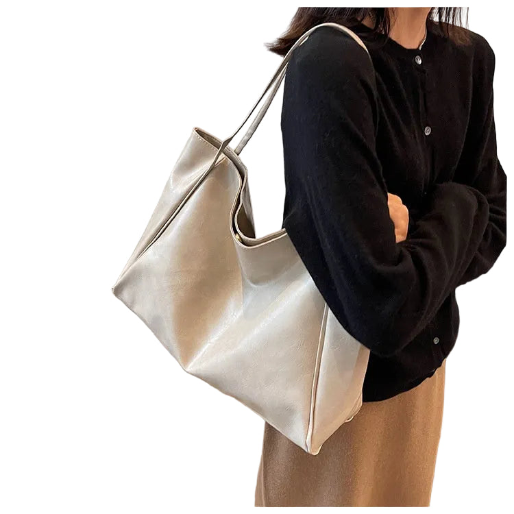 Person holding a beige handbag on a white background
