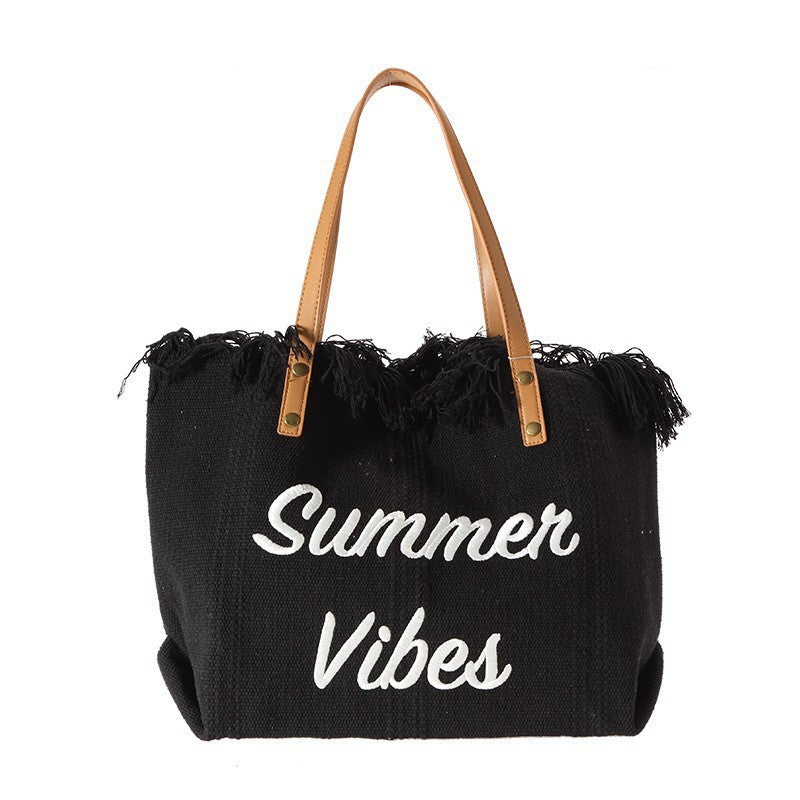 Black tote bag with 'Summer Vibes' text and fringes on a white background