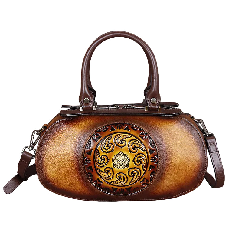 Brown leather handbag with decorative emblem on a white background