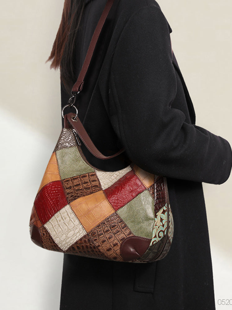 Patchwork handbag with a textured strap worn by a person in a black coat.