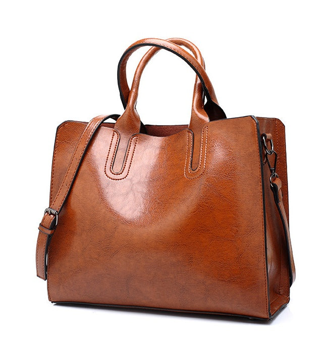 Brown leather handbag with a shoulder strap on a white background