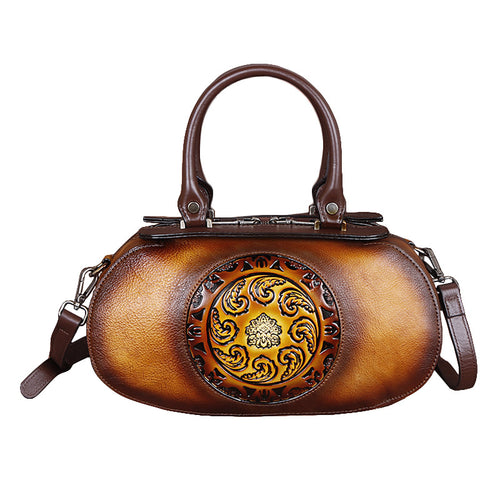 Brown leather handbag with decorative emblem on a white background