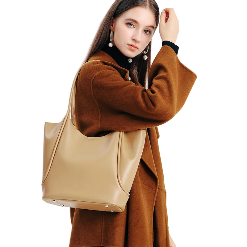 Woman in a brown coat holding a beige tote bag against a white background