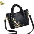 Black handbag with floral embroidery on a light White background