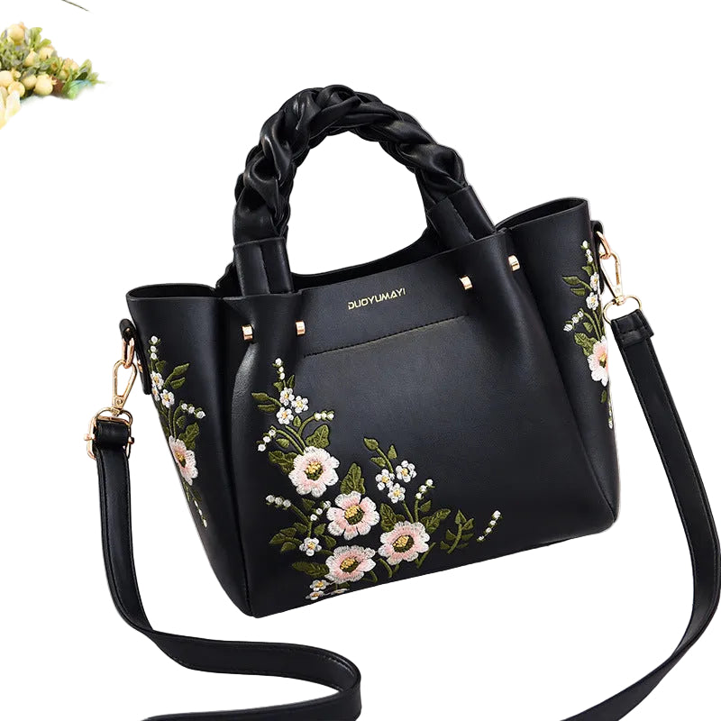 Black handbag with floral embroidery on a light White background