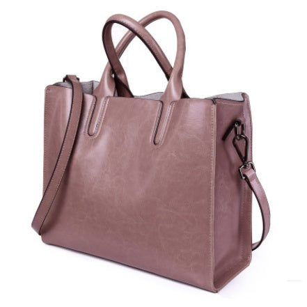 Brown leather tote bag with shoulder strap on a white background
