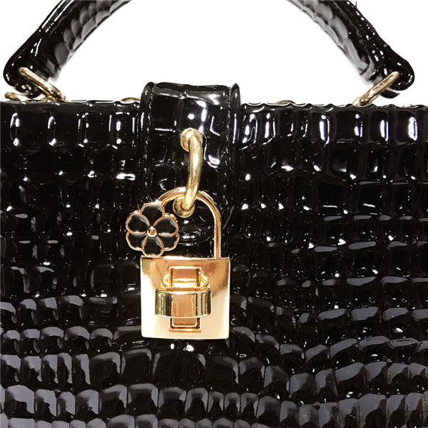 Black textured handbag with a gold padlock charm on a white background