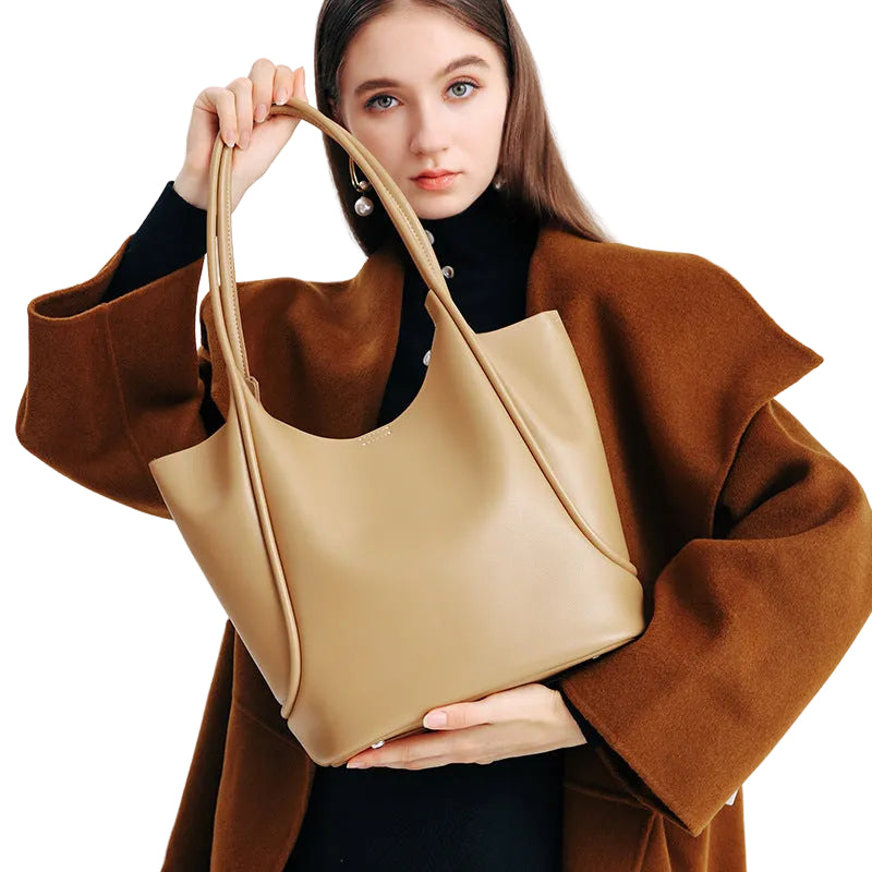 Woman holding a beige handbag against a white background