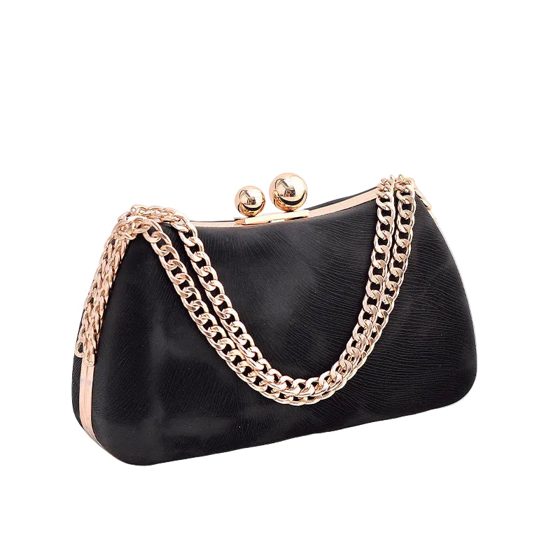 Black handbag with gold chain handle on a white surface