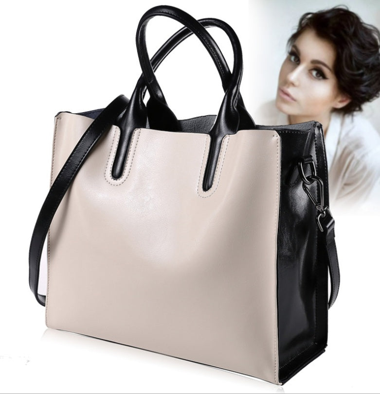 Beige handbag with black handles and strap on a white background