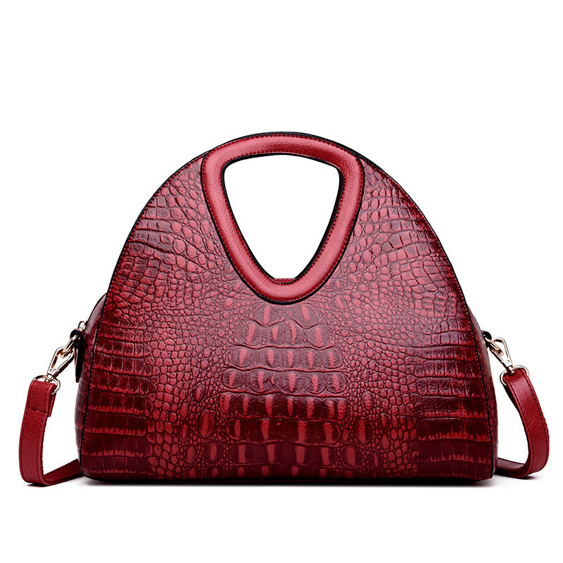 Red handbag with crocodile texture on a white background