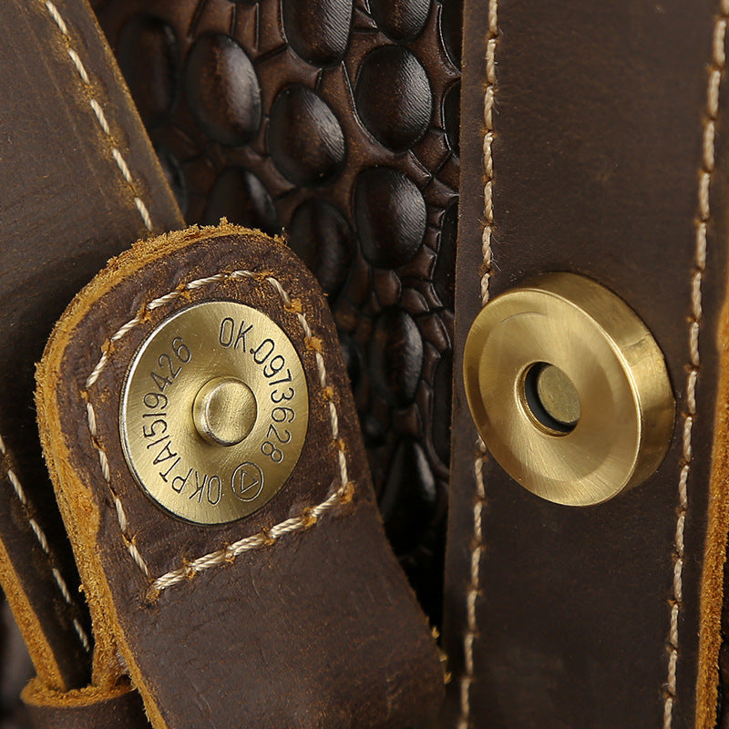 Close-up of a brown leather product with gold metal buttons and visible stitching.