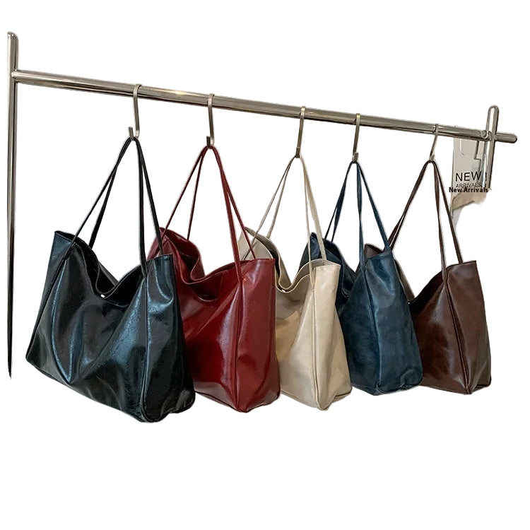 Five handbags in black, red, beige, blue, and brown hanging on a rack on a white background