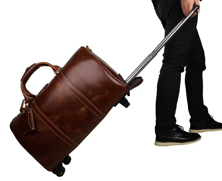 Brown leather suitcase with wheels being pulled by a person on a white background