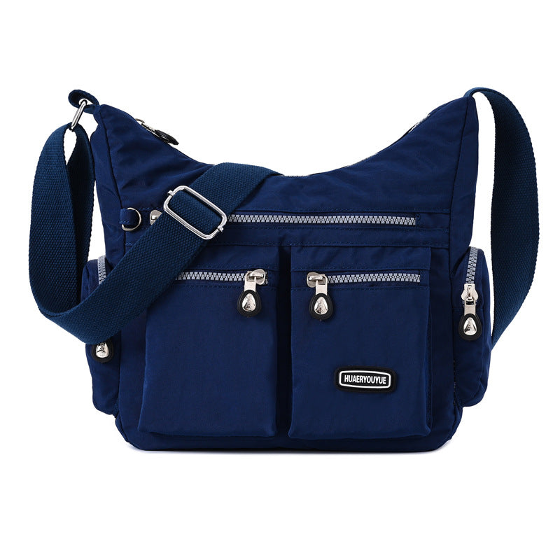 Blue shoulder bag with multiple zippers on a white background