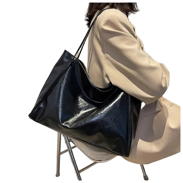 Person holding a black shiny handbagon a  white background