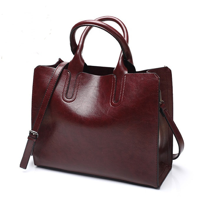 Brown leather handbag with a shoulder strap on a white background
