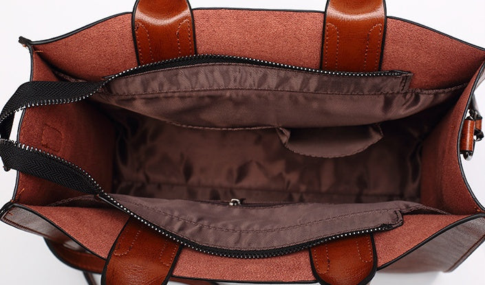 Brown leather handbag with open lid showing interior on a white background