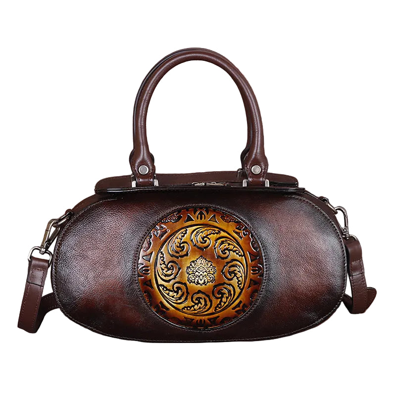 Brown leather handbag with decorative emblem on a white background