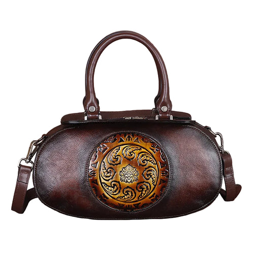 Brown leather handbag with decorative emblem on a white background