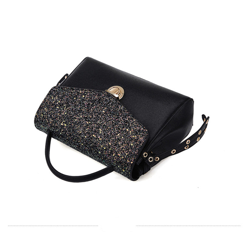 Black handbag with glittery flap and gold accents on a white background