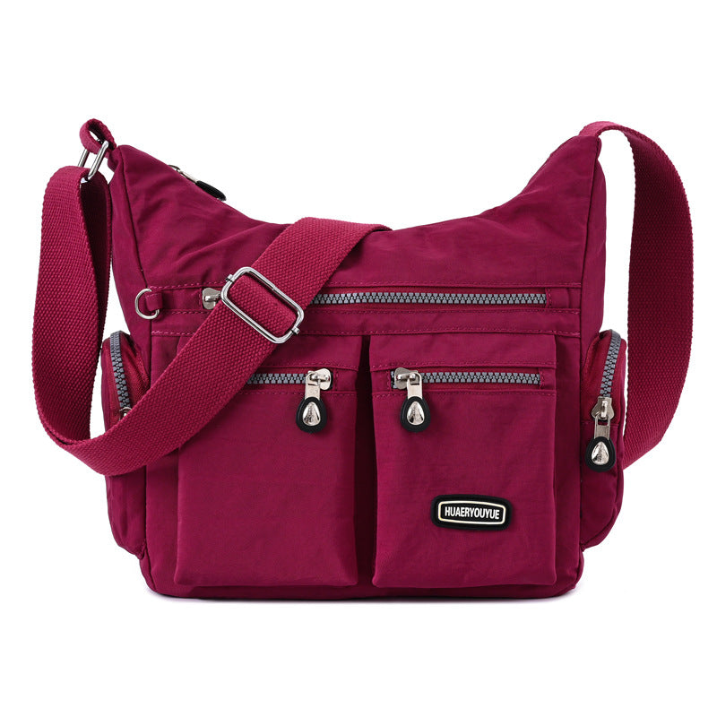 Red shoulder bag with multiple pockets and zippers on a white background