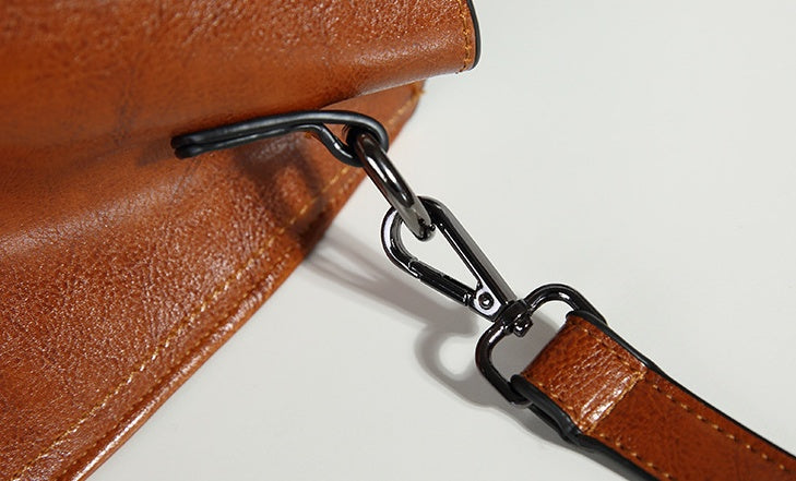 Close-up of a brown leather bag with a metal clasp on a white background