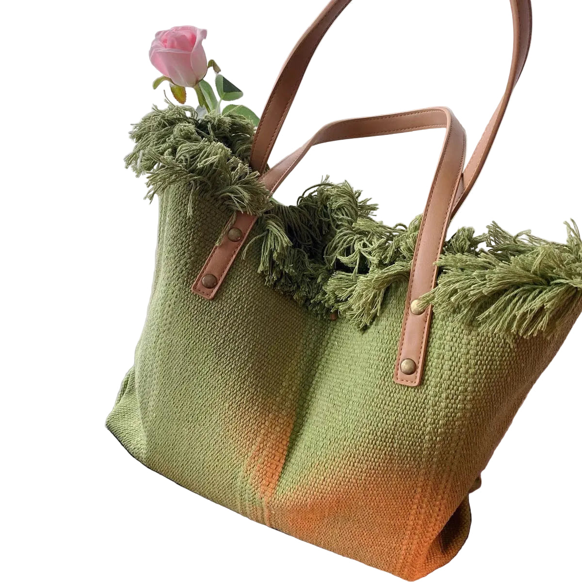 Green textured tote bag with fringe and a pink rose on a white background