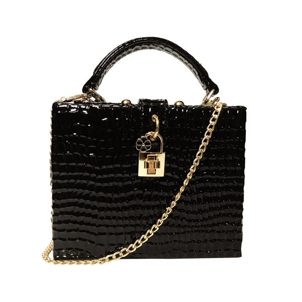 Black textured handbag with a gold chain and lock on a white background