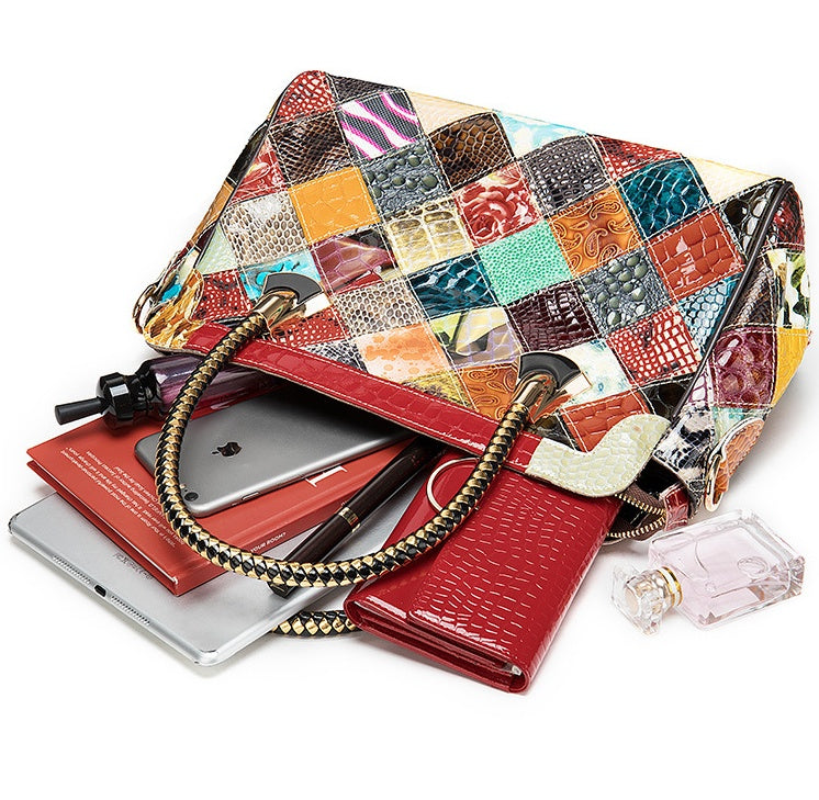 Colorful patchwork handbag with a red interior, containing a phone and other items on a white background.