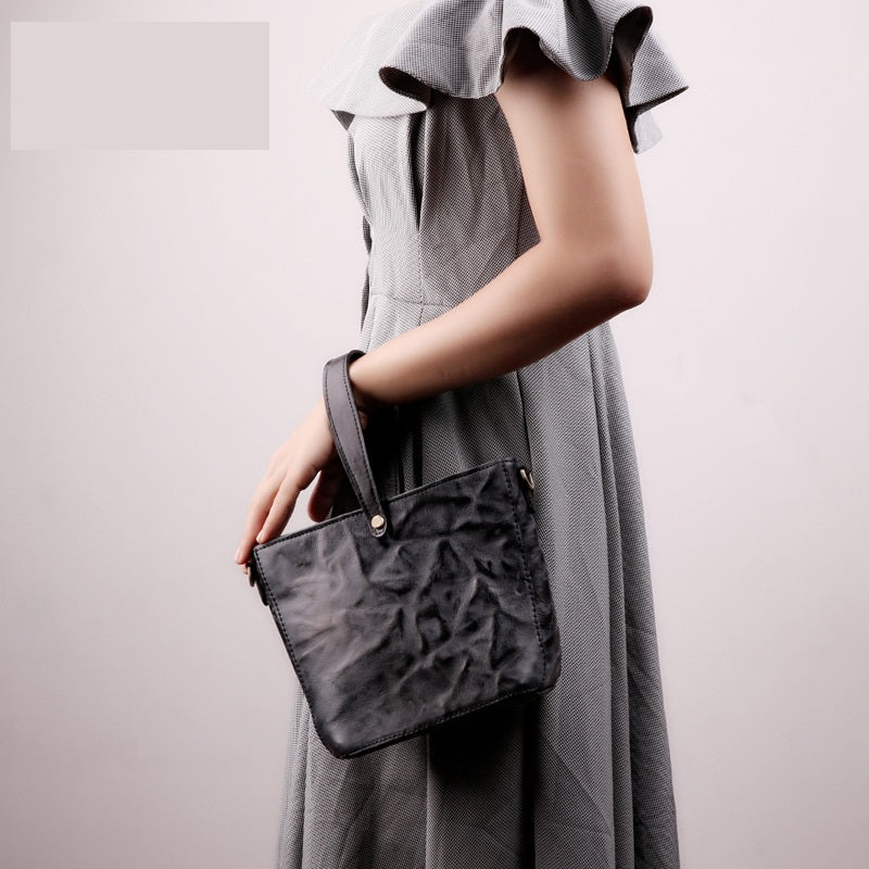 Person holding a textured black handbag against a plain background